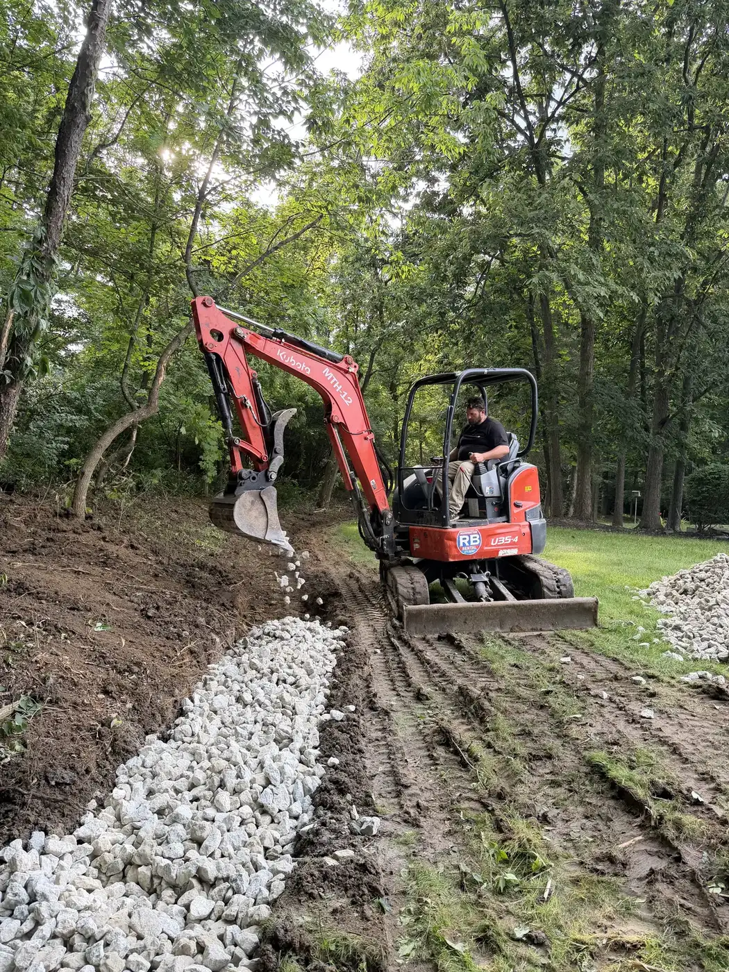 Phelps excavator building a gravel drainage trench