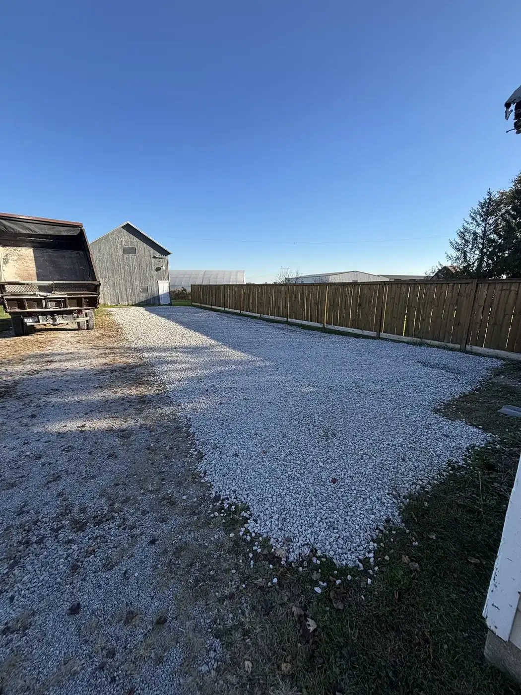 Fresh gravel spread along a fence line driveway by Phelps